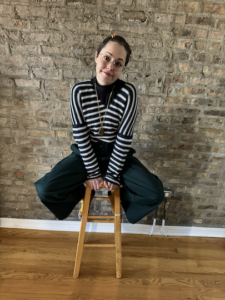 Lauren Plug, founder of Copy by LP in a blue and white striped sweater sitting on a stool