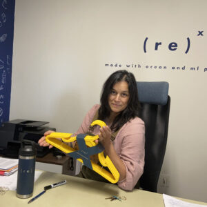 Paulina Quintana, founder of REX holding a pack of yellow recycled plastic hangers